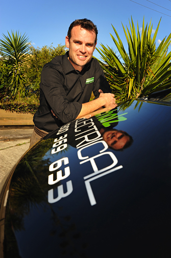 Side view of Michael Scholz, Managing Director of Scholz Electrical leaning on the hood of an electrician van printed with Scholz Electrical's brand logo