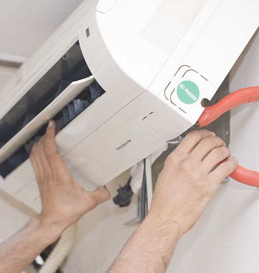 Scholz Electrical's electrician opening up the air conditioner with a pair of pincer pliers